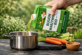 Wlewanie bulionu warzywnego bio do garnka ze stali nierdzewnej na tle warzyw