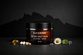 Słoik kremu na noc z retinolem na czarnym tle z kwiatem i kapsułkami