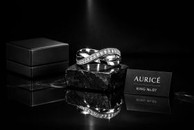 Srebrny pierścionek z cyrkoniami na czarnym kamieniu obok pudełka i wizytówki