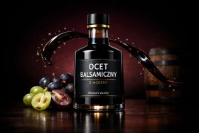 Butelka octu balsamicznego z Modeny z rozpryskującym się płynem i winogronami będąca przykładem na wizualizacje produktowe