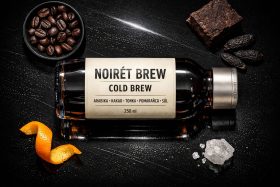Butelka kawy cold brew z ziarnami kawy, skórką pomarańczy, solą i kawałkiem czekolady