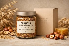 Słoik granoli rzemieślniczej z orzechami laskowymi i miodem obok kartonowego opakowania