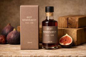 Butelka i pudełko z rzemieślniczym octem figowym na tle drewnianych klocków i świeżych fig