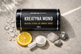 Czarny pojemnik kreatyny mono z miarką proszku i plasterkiem cytryny na piasku