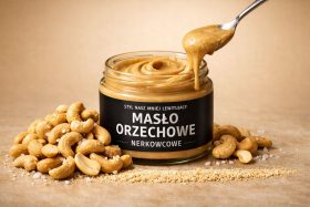 Słoik masła orzechowego nerkowcowego z łyżką i orzechami nerkowca obok