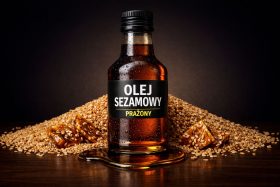 Butelka prażonego oleju sezamowego na tle ziaren sezamu i słodyczy sezamowych będąca przykładem na wizualizacje produktowe